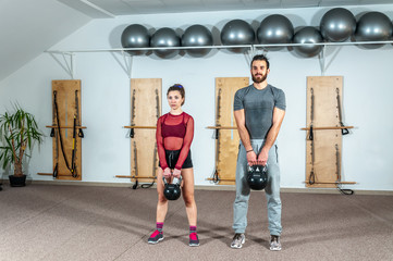 Fototapeta na wymiar Young positive and active fit couple workout kettlebell fitness exercise in the gym, selective focus