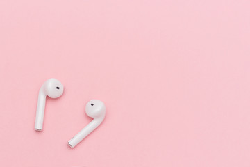 White wireless Bluetooth headphones on pink paper background. Template for text or your design. Flat lay Top view Copy space