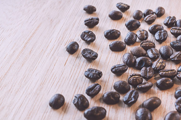 Close up of Coffee beans on wood background in vintage tone color style, selective focus (detailed close-up shot)