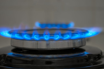 A bright blue flame burns in the gas stove. The gas burner is close-up.