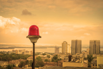 A red alarm is on the roof of a tall building. Obstruction Lights on the background of urban...