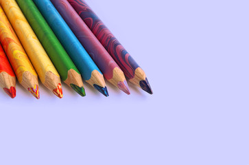 Color pencils on a blue background. Spectrum of a rainbow. Back to school. Selective focus, close-up.