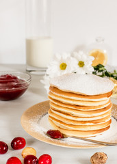 A stack of homemade pancakes for Breakfast with cranberry jam with milk