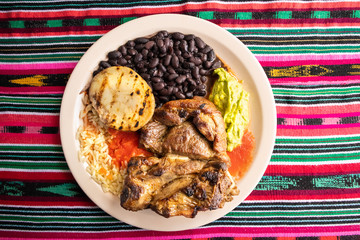 Lunch Plate of Grilled Meat, Beans, Rice, Potato in Guatemala with Decorative Tablecloth (Close-up)