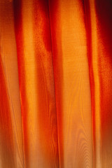 Vertical folds on orange organza curtains