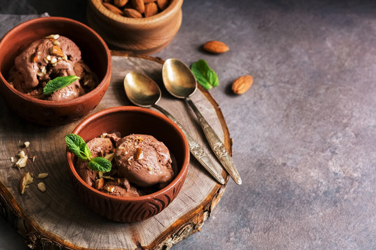Homemade chocolate ice cream with almonds and mint leaves on a dark rustic background. Selective focus, copy space