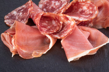 Italian prosciutto crudo or spanish jamon and sausages. Raw ham on stone cutting board