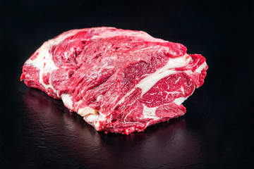Roher dry aged Wagyu Rindernacken als closeup vor schwarzen Hintergrund mit Textfreiraum