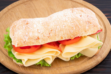 Ciabatta sandwich with lettuce , prosciutto and  cheese on wooden board