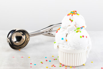 plate of vanilla ice cream scoop swith sprinkles and waffle cones