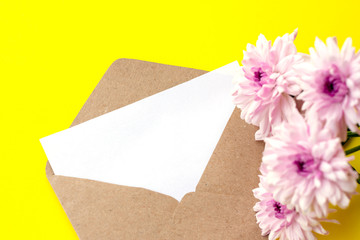 Love envelope with blank letter and pink chrysanthemum flowers on bright yellow bacground. Copy space