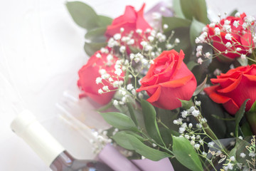 bouquet of red roses with a bottle of wine on a white background in white blurred light
