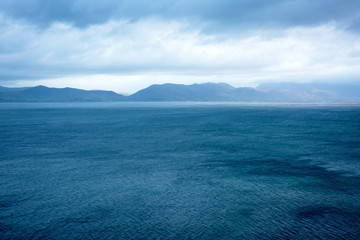 Blue natural background with clouds, mountains and sea