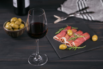 Black stone platter with slices of cured ham or Spanish jamon serrano or Italian prosciutto crudo