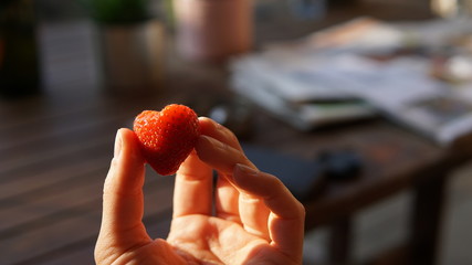Holding a heart-shaped strawberry - 264264780