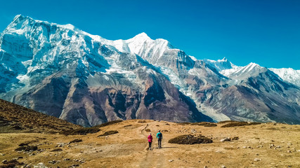 A couple walking on the Annapurna Circuit Trek, Himalayas, Nepal. Annapurna chain in the back,...