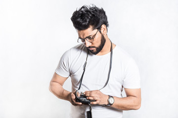 Portrait of a handsome young stylish man with beard taking photo on a vintage camera.