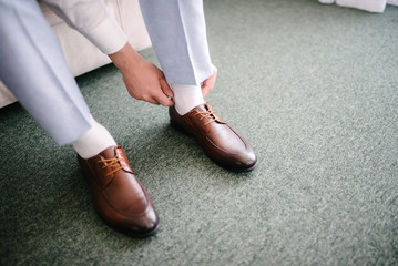 A man in a suit puts shoes on his feet.