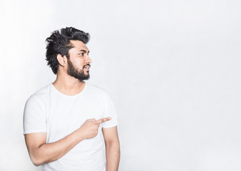 Handsome young man indicates with forefinger at blank copy space.