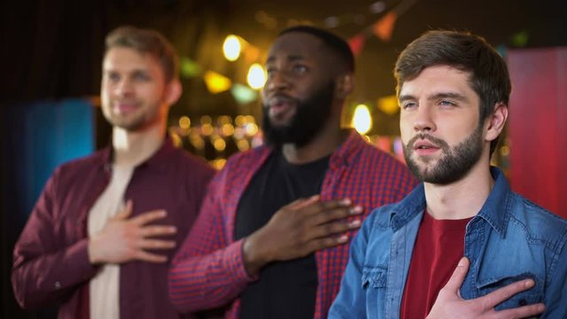 Multiracial Friends Singing National Anthem Before Football Game Beginning, Pub