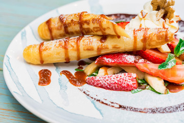 Close up delicious dessert with waffle rolls, ice cream and strawberries