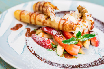 Close up delicious dessert with waffle rolls, ice cream and strawberries