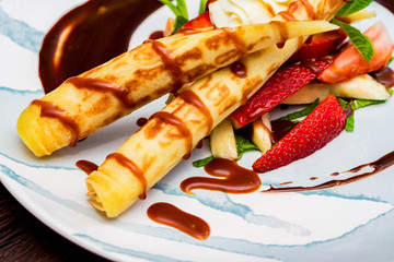 Close up delicious dessert with waffle rolls, ice cream and strawberries