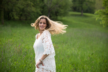 Fototapeta na wymiar Young happy caucasian woman smiling in a meadow full of flowers. Nature and happiness concepts