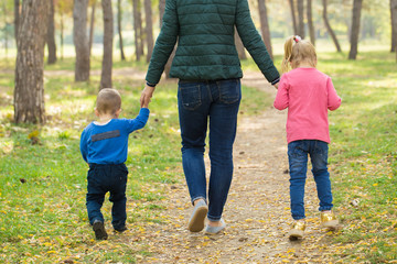 Mom, son and daughter walking in the park at sunset