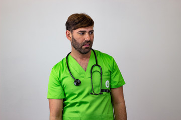 Portrait of male veterinary doctor in green uniform with brown hair looking disgusted, facing...