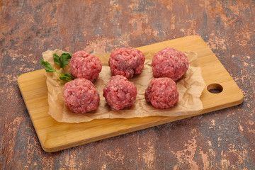 Raw meatball over wooden background