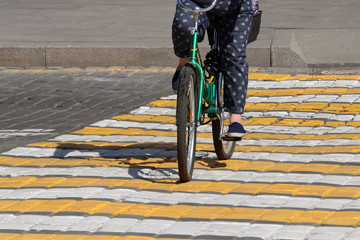 Woman riding a bike on a city street. Female legs and bicycle wheels on pedestrian crossing,...