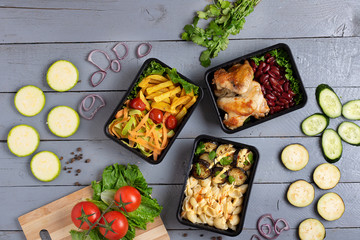 kitchen board and garden raw vegetables with roast chicken, food containers on rustic table, flat lay. Seletive focus