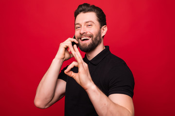 Portrait of a smiling man standing over red background, talking on mobile phone
