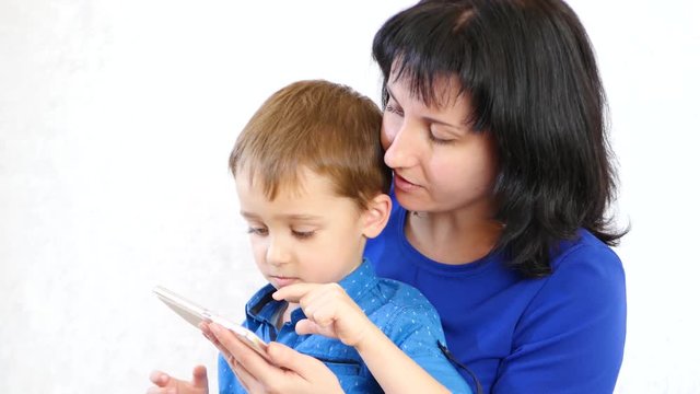Young mother and her son playing smartphone and smiling, on white background
