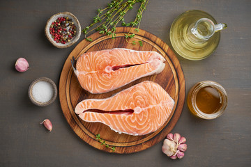 Two salmon steaks, top view, close up. Fish fillet, large sliced portions  on a chopping board on dark table.