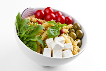Pasta with fresh vegetables in a white plate on a white background