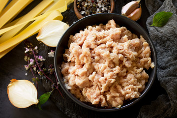 Minced meat, pasta and ingredients for cooking minced meat in a bowl on a slate.