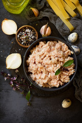 Minced meat, pasta and ingredients for cooking minced meat in a bowl on a slate. Top view flat lay background. Copy space.