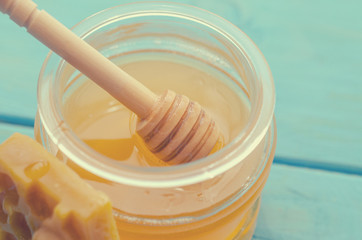 Honey and honey accessories for its use on a blue wooden background.