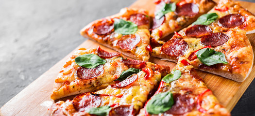Obraz na płótnie Canvas Pepperoni Pizza with Mozzarella cheese, salami, pepper, Spices and Fresh spinach. Italian pizza on Dark grey black slate background