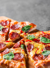 Pepperoni Pizza with Mozzarella cheese, salami, pepper, Spices and Fresh spinach. Italian pizza on Dark grey black slate background