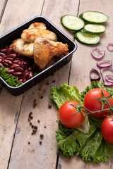 ready dish to eat in lunch boxes, raw vegetables around, food containers on wooden table