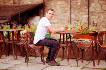 Happy man having coffee break at outdoors cafe in old europen city