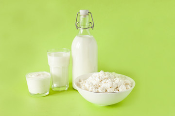 milk in a bottle sour cream cottage cheese and a glass of milk on a green background