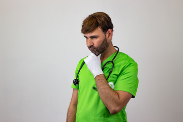 Portrait of male veterinary doctor in green uniform with brown hair frustated, facing forwards and...