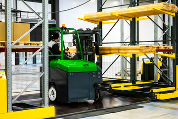 The forklift operator is loading wood boards. Forklift truck. The loader picks up boards. Shelving warehouse. The loading of the goods. Storage. Warehouse storage. Turnover logistics.