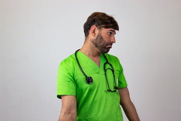 Portrait of male veterinary doctor in green uniform with brown hair unhappy, facing forwards and...