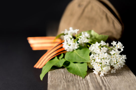 White lilac flowers on the wood background. Bouquet with a ribbon of St. George for the celebration of Great Victory Day.