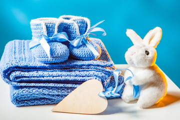Pregnancy. The concept of waiting for the baby. Knitted baby shoes. Soft toy rabbit for the baby. Heart symbol. Clothes for the newborn. Newborn. Baby. Motherhood.